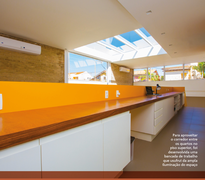 Para aproveitar o corredor entre os quartos no piso superior, foi desenvolvida uma bancada de trabalho que usufrui da ampla iluminação do espaço